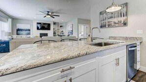 A modern kitchen with a granite countertop, white cabinetry, and a dishwasher. - Rooftop Patio, Hot Tub, EV charging, Mtn views, close to AFA! (Palmer Lake)