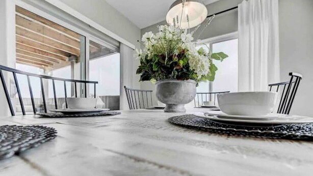 A dining table with a white tablecloth, a potted plant, and a bowl of flowers. - Rooftop Patio, Hot Tub, EV charging, Mtn views, close to AFA! (Palmer Lake)