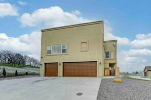 A two-story building with a beige exterior, two garage doors, and a small porch area. - Rooftop Patio, Hot Tub, EV charging, Mtn views, close to AFA! (Palmer Lake)