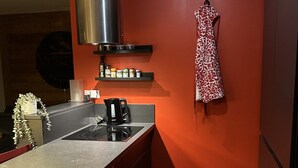 A modern kitchen with a red accent wall, a stainless steel range hood, a kettle, and a hanging dress. - Walking distance of all lifts/town for summer and winter fun! Sleeps 9 (Morzine)
