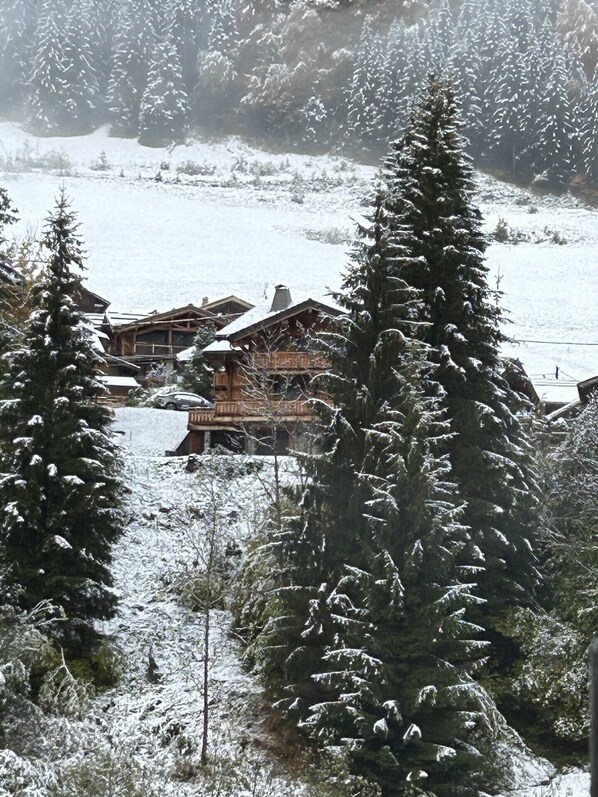 A wooden lodge with a snow-covered roof, surrounded by tall evergreen trees. - Walking distance of all lifts/town for summer and winter fun! Sleeps 9 (Morzine)