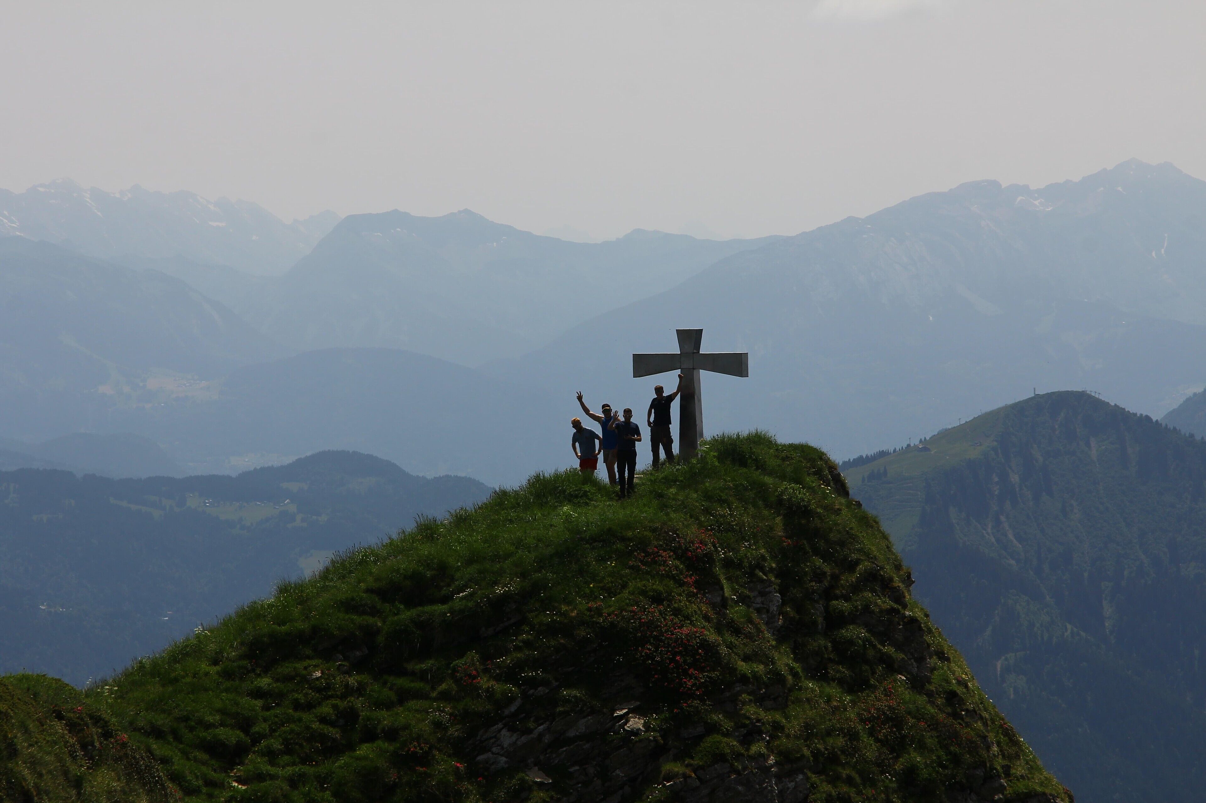 Ein Kreuz auf einem Hügel vor einer Berglandschaft.