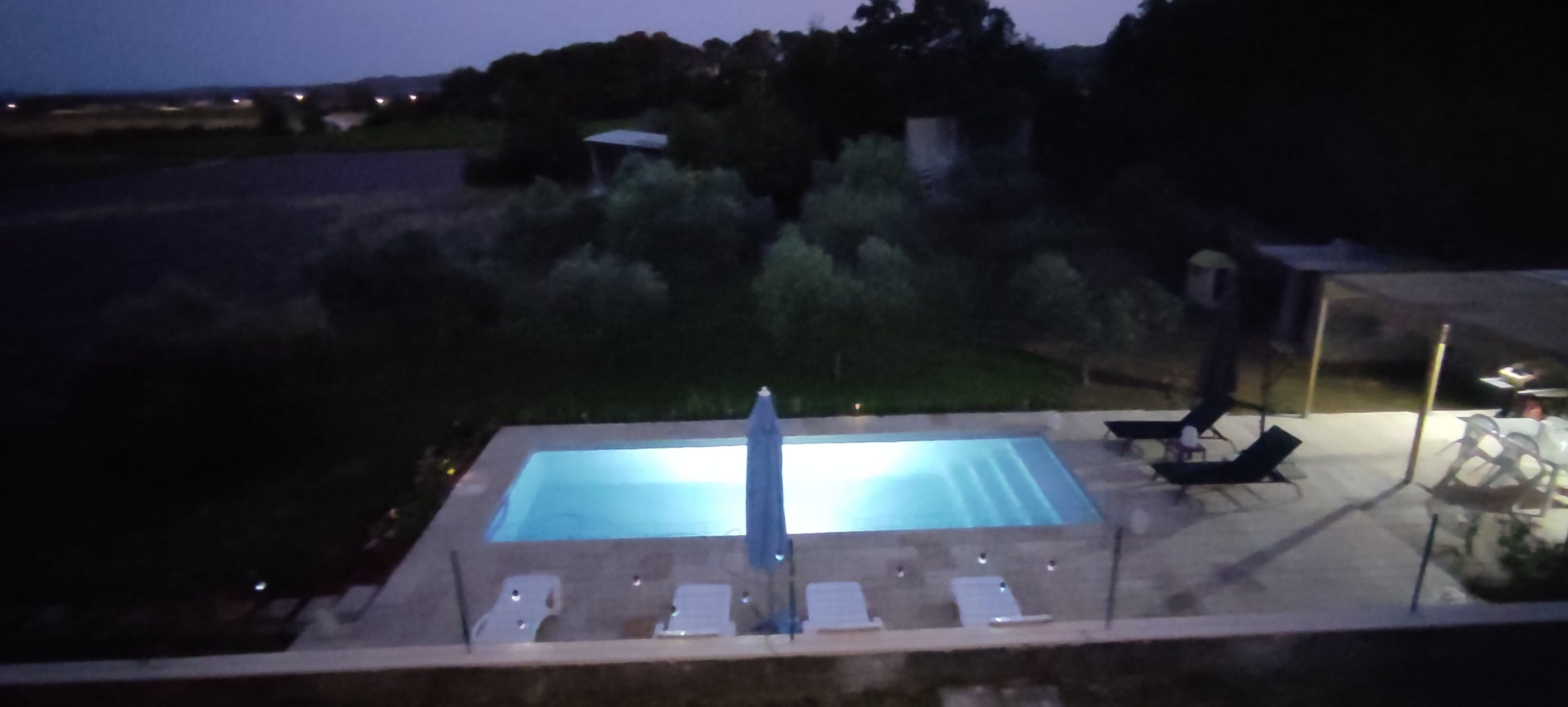 A swimming pool with lounge chairs and a sun umbrella.