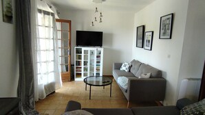 Uma sala de estar com sofá, mesa de centro, televisão e estante de livros.