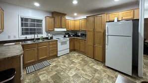 Una cucina con mobili in legno, un frigorifero bianco, un fornello e un forno a microonde.
