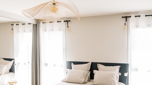 A bedroom with a large bed, a hanging light fixture, and a view of the outdoors through sheer curtains. - Villa Moka - private pool (Saumane-de-Vaucluse)