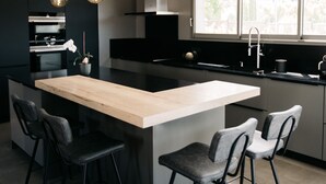 A modern kitchen with a central island, bar stools, and pendant lighting. - Villa Moka - private pool (Saumane-de-Vaucluse)