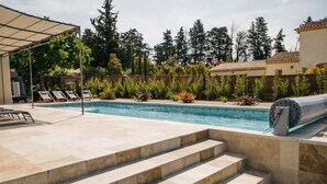 A swimming pool with steps leading to the water, surrounded by a patio area with lounge chairs and a covered seating area. - Villa Moka - private pool (Saumane-de-Vaucluse)