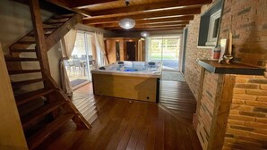 Habitació acollidora amb escala de fusta, banyera d'hidromassatge i paret de rajola.
