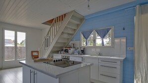 A modern kitchen with a central island, white cabinetry, a microwave, and a coffee maker. - Charming family home- natural pool (Gujan-Mestras)