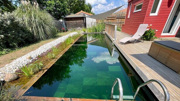 A swimming pool with a wooden deck and a metal faucet. - Charming family home- natural pool (Gujan-Mestras)