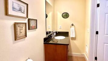 A bathroom with a sink, mirror, framed pictures, and a towel rack.