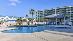 Un hotel con piscina, sillas de descanso y una zona de estar cubierta.