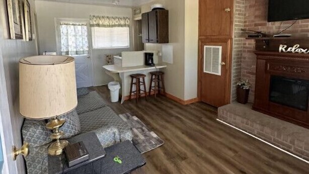 A compact living space with a kitchenette, a dining area, a fireplace, and a ceiling fan. - Quiet Cottage located in the heart of Burr Oak State Park - #4 (Glouster)