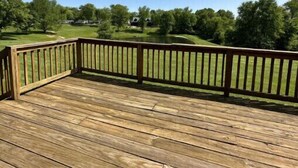 A wooden deck with a railing overlooking a golf course. - Quiet Cottage located in the heart of Burr Oak State Park - #4 (Glouster)