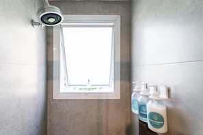 A bathroom with a window, a security camera, and bottles of conditioner. - Studio Vitreo 66 (São Paulo)