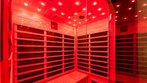 Un sauna aux couleurs rougeoyantes, avec des bancs en bois et un plafond en pente.