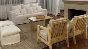 Ein modernes Wohnzimmer mit einem weißen Sofa, Holzstühlen, einem Couchtisch und einem Kamin.