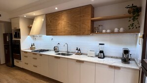 Eine moderne Küche mit einer langen Arbeitsplatte, eingebauten Schränken und einer Holzbalkendecke.