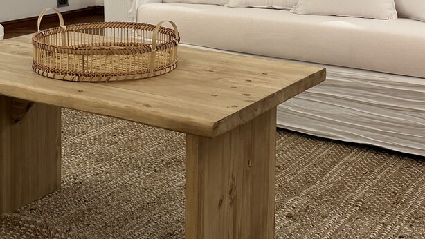 Ein modernes Wohnzimmer mit einem weißen Sofa, einem Holztisch und einem gewebten Korb.