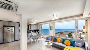 A modern apartment with a kitchen, dining area, and a living room with a view of the beach. - Mackenzie Eftyhia Beachfront Suite (Larnaca)