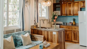 A spacious kitchen with wooden cabinets, a central island, and a dining area with a wooden table and blue patterned sofa.