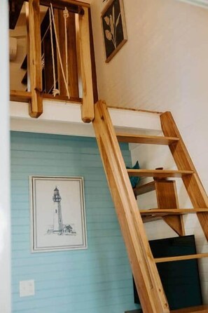 Una escalera de madera con barandilla que lleva a un altillo.