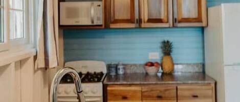 A kitchen with granite countertops, wooden cabinets, a stainless steel sink, and a hanging light fixture.