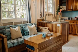 Una cocina acogedora con una isla de madera, un sofá azul estampado y una ventana con cortinas.