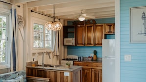 A spacious kitchen with wooden cabinets, a central island, and a dining area with a wooden table and blue patterned sofa.