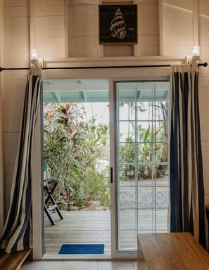 A hotel entrance with a glass door, a wooden bench, and a view of the garden.