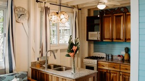 A cozy kitchen with wooden cabinets, a central island, a built-in oven, and a dining area with a patterned sofa.