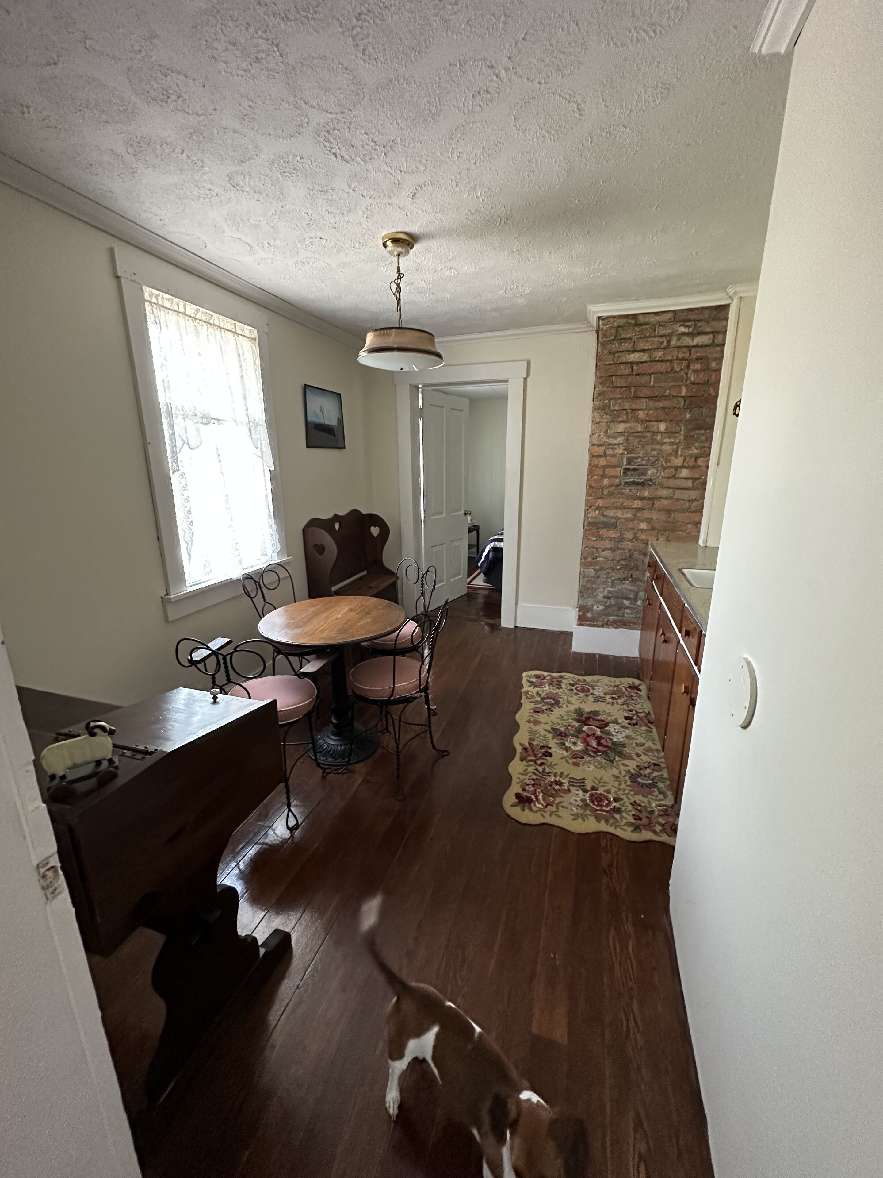 Un comedor con una mesa y sillas de madera, un banco y una alfombra.
