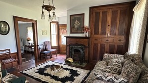 Un salón tradicional con chimenea, sofá estampado, suelo de madera y un espejo grande.