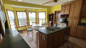 Una cocina con isla central, armarios de madera y comedor con sillas y mesa.