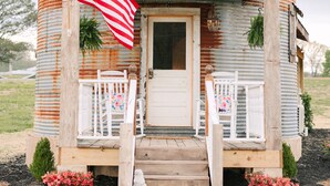Een rustieke houten hut met een veranda, een witte deur en een Amerikaanse vlag.