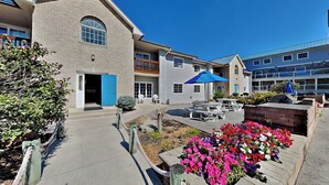 A courtyard with a brick building, outdoor seating, and a flower bed. - Wake, Swim, Repeat—Poolview Fun | 8 ppl | C4 (Put-in-Bay)