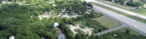An aerial view of a residential area with houses, a road, and a small airport. - Wake, Swim, Repeat—Poolview Fun | 8 ppl | C4 (Put-in-Bay)