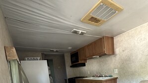 Een kleine keuken met houten kastjes, een magnetron en een spoelbak.