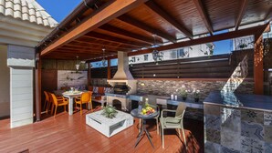 Une terrasse extérieure avec une plateforme en bois, un barbecue et un espace détente comprenant des chaises et une table.