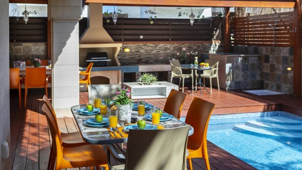 Un espace extérieur aménagé pour les repas, avec une piscine, une terrasse en bois et un barbecue.