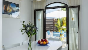 A dining area with a white table, a vase with flowers, and a fruit bowl. - Villa Alexa Protaras (Paralimni)