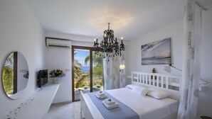 Quarto com cama, uma grande janela, um candelabro, um quadro e vista para o exterior.