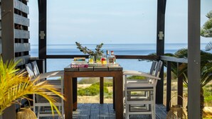 Um deck de madeira com uma mesa posta para dois, com vista para a praia.