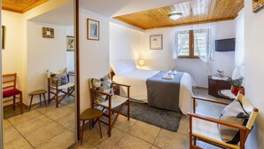 A bedroom with a bed, a desk, a chair, a TV, and a window. - Troodos Riverside Cottage (Kato Amiantos)