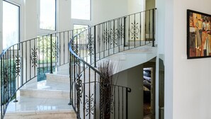 Un intérieur spacieux agrémenté d’un escalier en colimaçon, de grandes fenêtres et d’un tableau au mur.