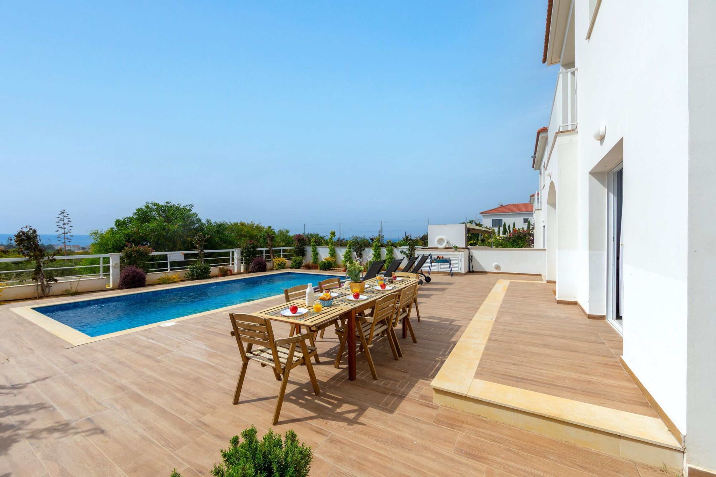 Ein Poolbereich mit Esstisch und Stühlen, einem Pool und Meerblick.