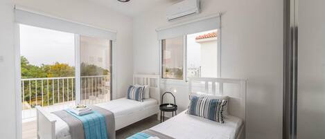 Un dormitorio moderno con dos camas individuales, un balcón y un ventanal grande.