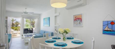 A dining area with a round table set for four, surrounded by wicker chairs.