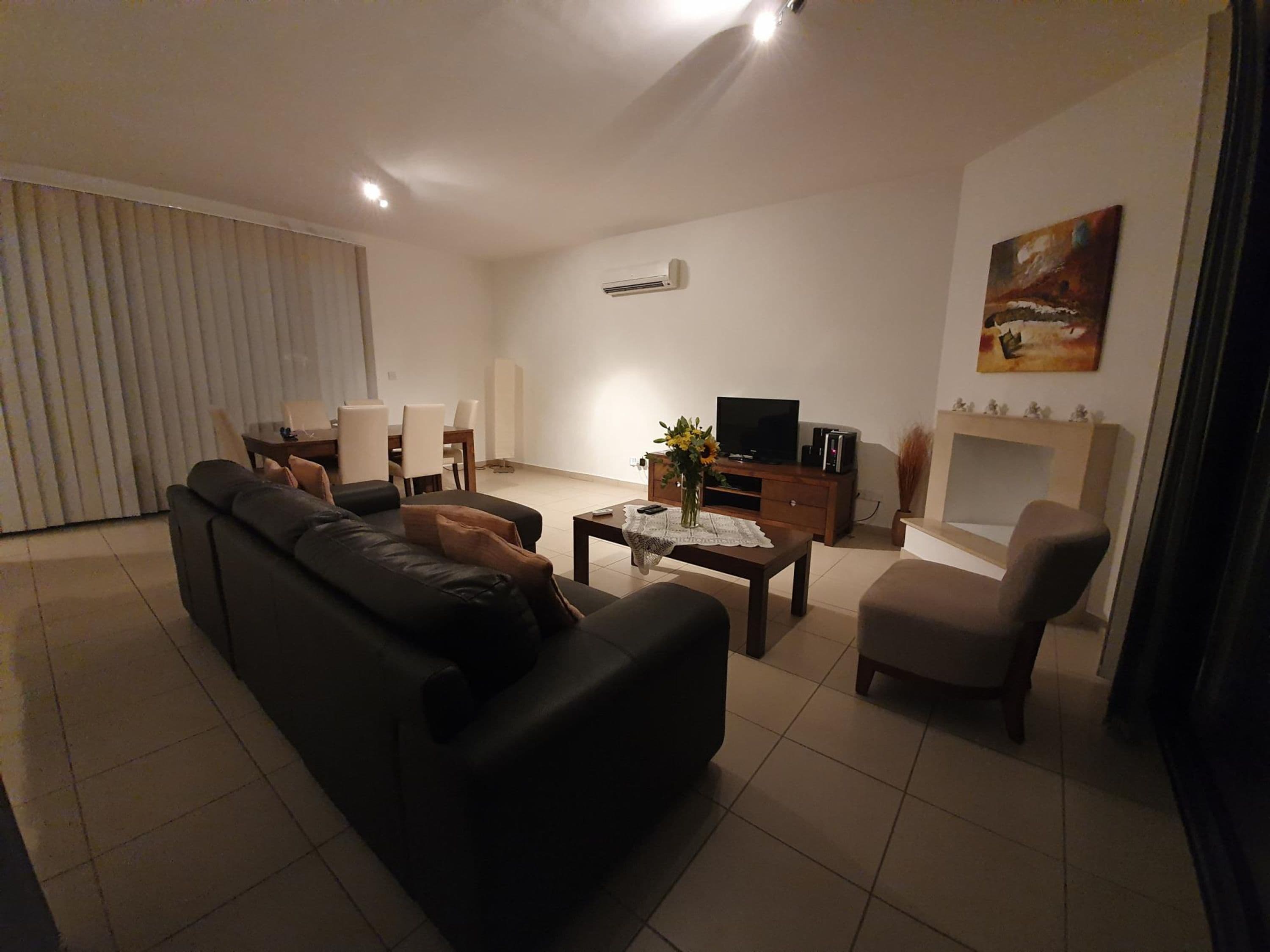Ein Wohnzimmer mit einer Couch, einem Couchtisch, einem Fernseher und einem Kamin.